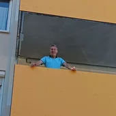 Bewohner steht auf einem gelben sybkon Balkon und genießt den neuen Wohnraum