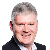 Porträtfoto eines lächelnden Mannes im Anzug vor weißem Hintergrund, aufgenommen für eine Projektreferenz von INNOVAMETALL