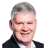 Porträtfoto eines lächelnden Mannes im Anzug vor weißem Hintergrund, aufgenommen für eine Projektreferenz von INNOVAMETALL