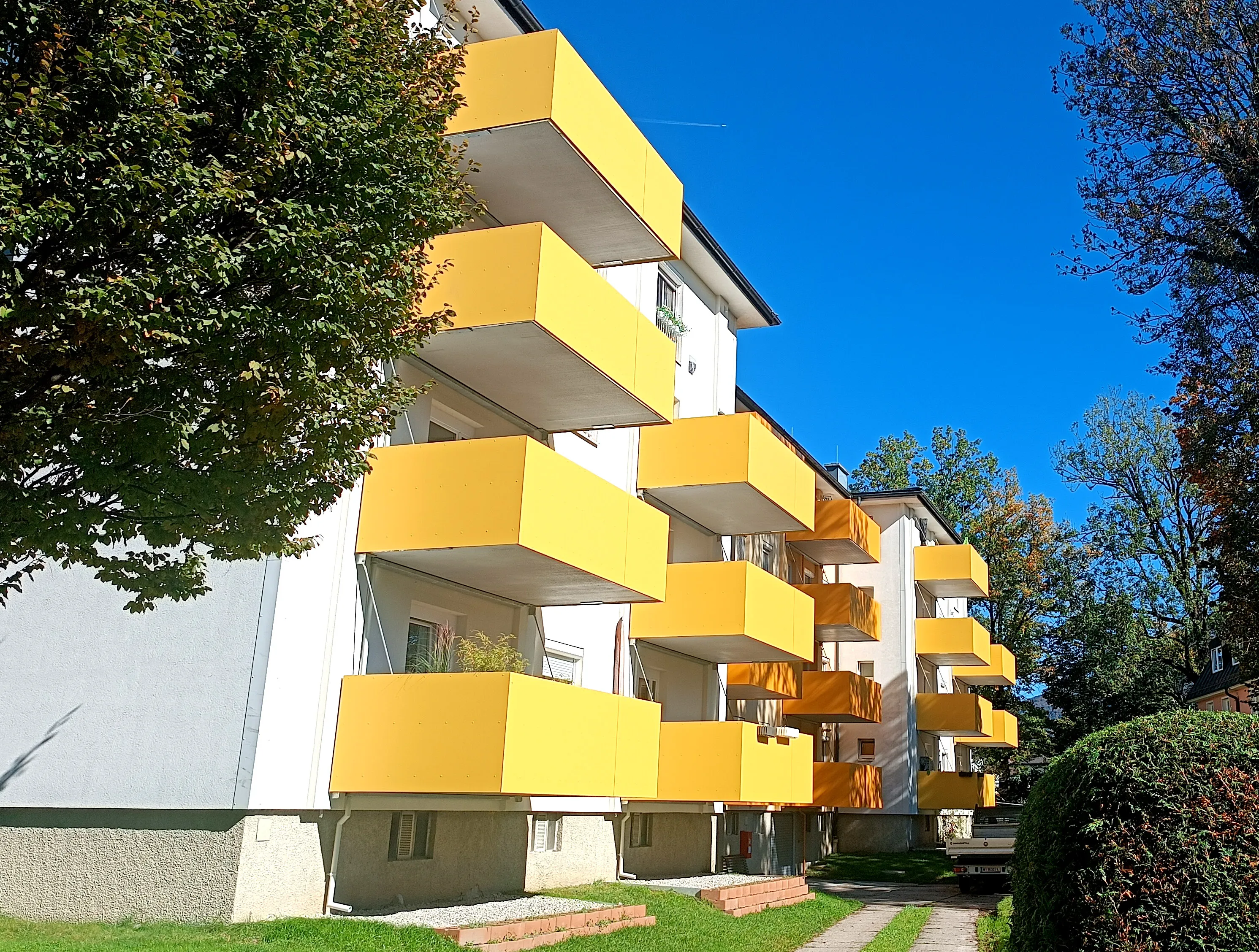 Mehrparteienhaus mit gelben sybkon Balkonmodulen bei Sonnenschein